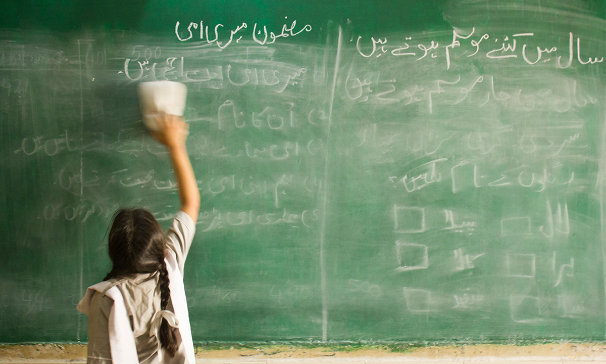 Child reaches up to clean chalkboard