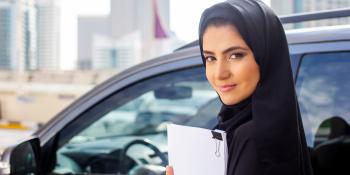 Saudi woman near a car with a clipboard